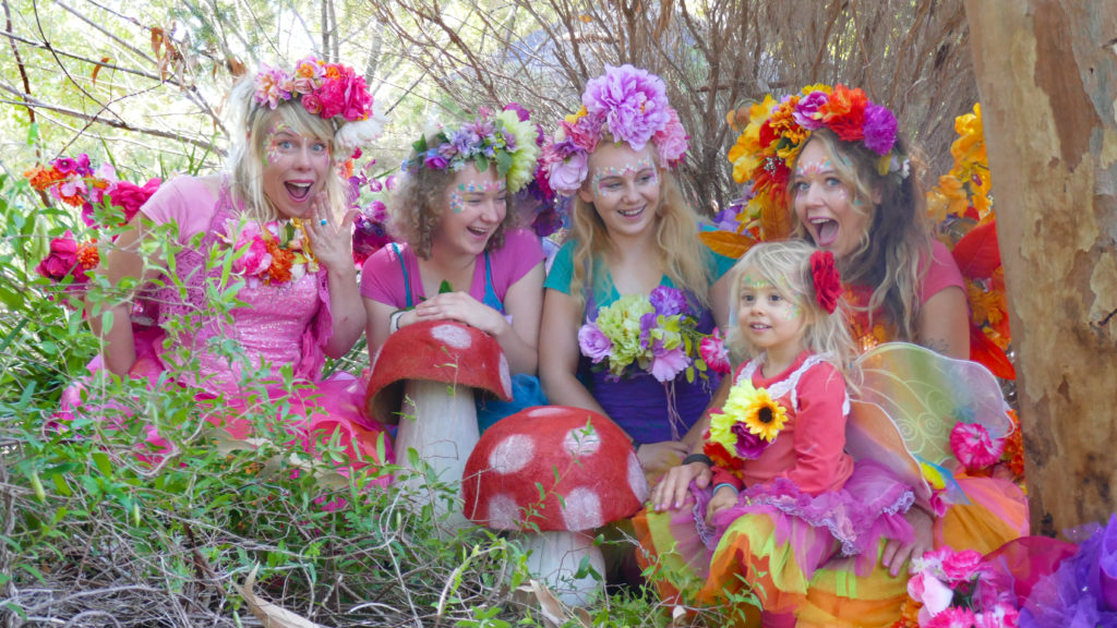 A group of children dressed as fairy posing in the woods.