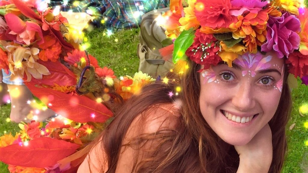 A girl in a flower crown posing for a photo.