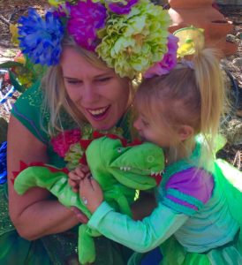 A woman dressed as a fairy holding a stuffed animal.