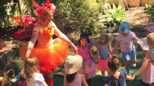 A group of children dressed up in fairy costumes in a garden.