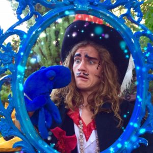 A man in a pirate costume holding a blue mirror.