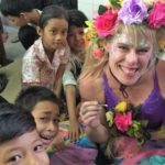 A woman with flowers on her head and a group of children.