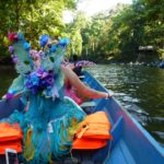 A woman dressed as a fairy is riding in a canoe.