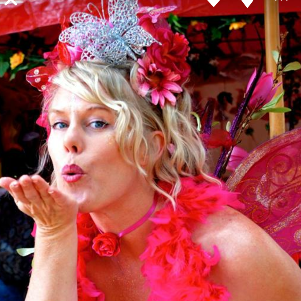 A woman dressed as a fairy blowing a kiss.