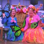 Two women dressed in colorful costumes and holding guitars.