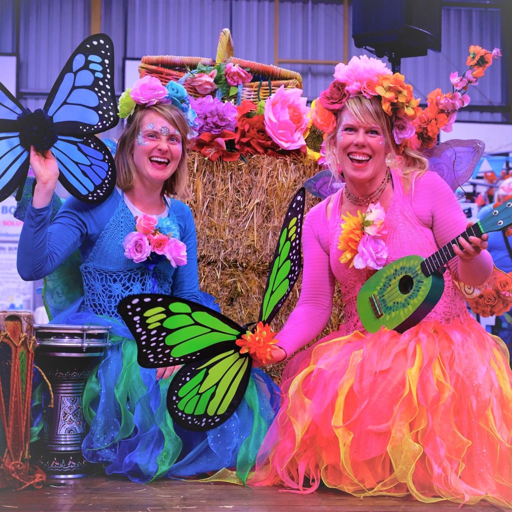 Two women dressed in colorful costumes and holding guitars.