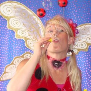 A woman dressed as a ladybug blowing bubbles.