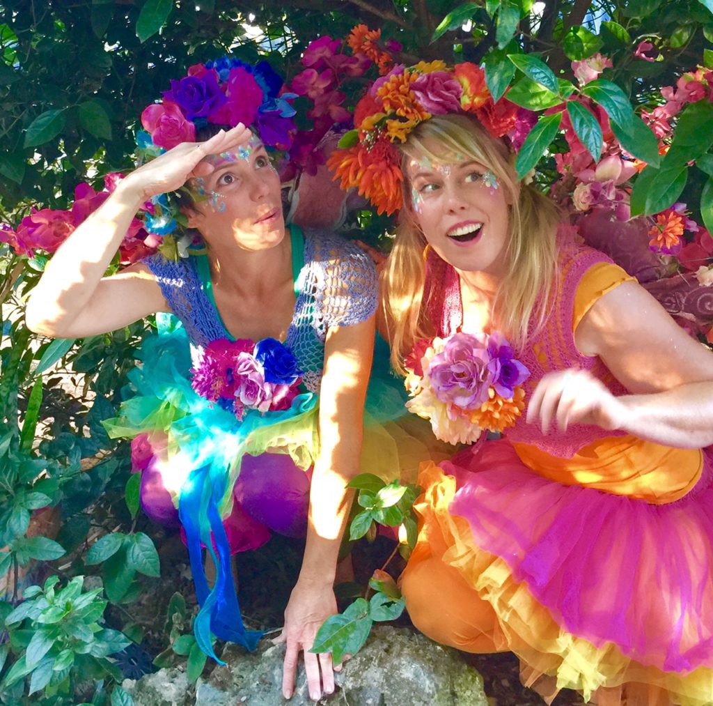 Two women dressed in colorful fairy costumes are posing for a photo.