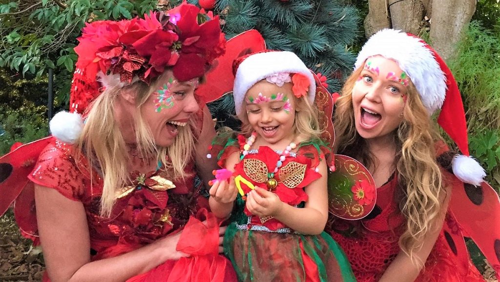 Three women dressed up in santa claus costumes with a little girl.