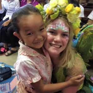 A young girl is hugging a woman dressed as a fairy.