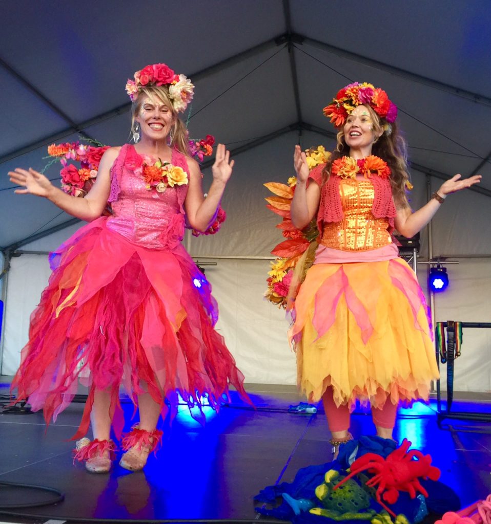 Two women wearing colorful clothing on a stage.