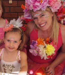 A woman and two girls with flowers on their faces.