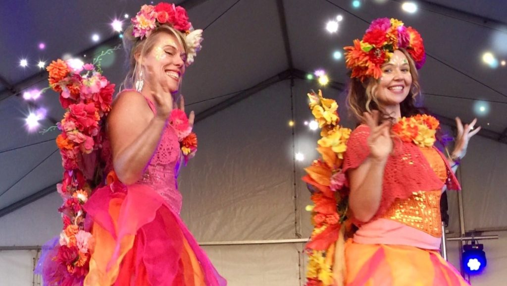 Two women dressed in colorful costumes on stage.