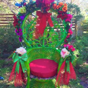 A green wicker chair decorated with flowers and bows.