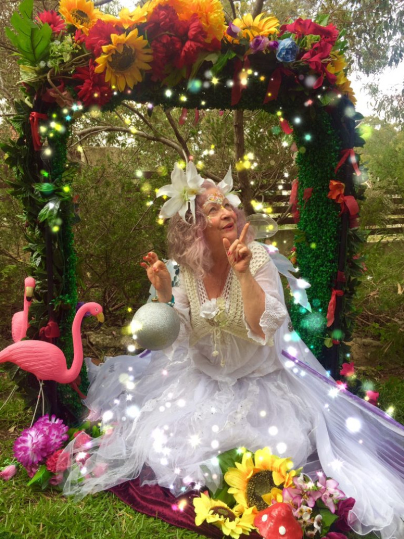 A woman in a white dress sits in a garden with flowers and flamingos.