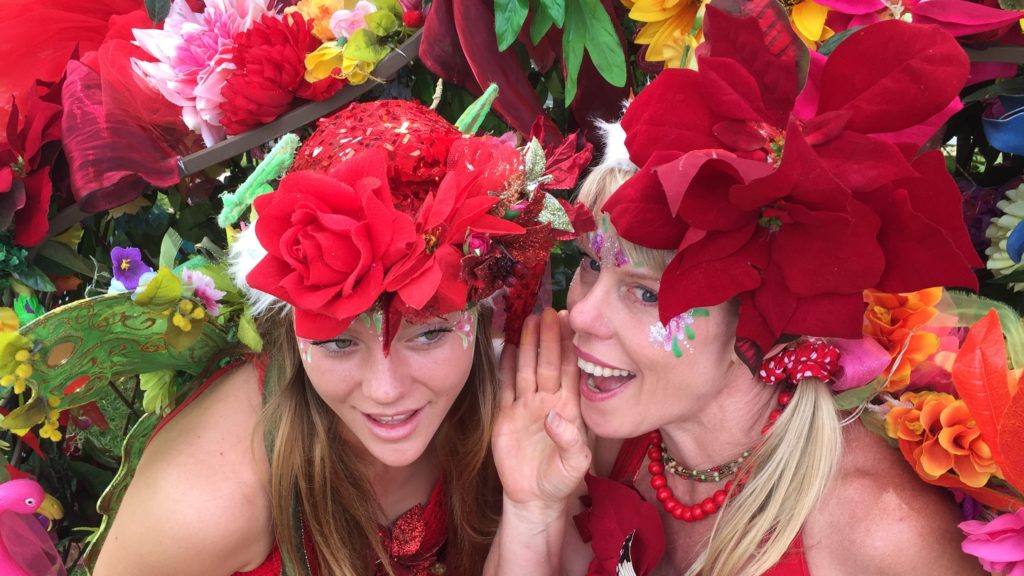 Two women wearing red hats and flowers.