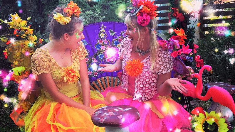 Two girls in colorful costumes sitting on a bench.