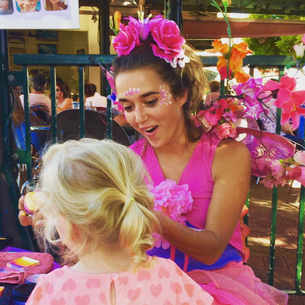 A woman in a garment with flowers on her head and a little girl in a pink dress.