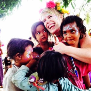 A woman with face paint and a group of children.