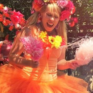 A woman in an orange dress with flowers in her hair.