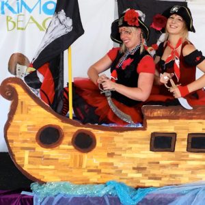 Two women dressed as pirates on a wooden boat.