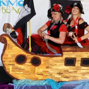 Two women dressed as pirates on a wooden boat.