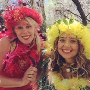 Two women posing for a photo in a forest.