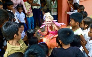 A woman in a pink dress sitting in a circle with children.