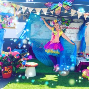 A woman in a colorful costume is standing in front of a tent.