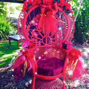 A red rattan throne decorated with flowers.