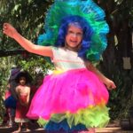 A little girl dressed up in a colorful hat.