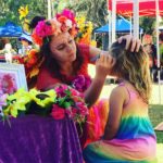 A woman is helping a little girl get her face painted.