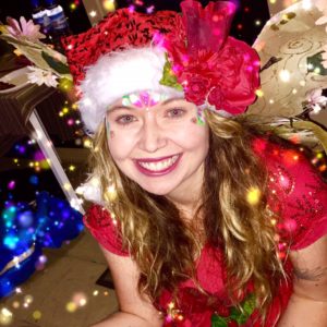 A woman in a santa hat is smiling at the camera.