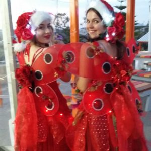 Two women dressed up in christmas costumes with santa hats.