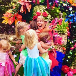 A woman in a fairy costume is hugging a group of children.