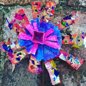 A flower made out of paper on a brick wall.