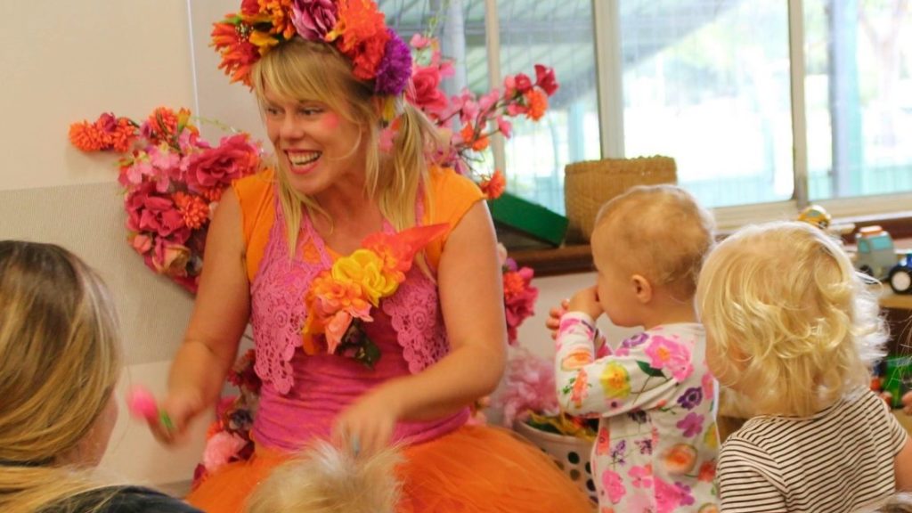 A woman dressed as a fairy is playing with a group of children.