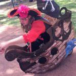 A man dressed as a pirate sits on a wooden boat.