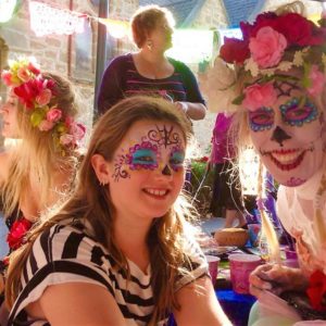 A group of girls with sugar skull face paint at a party.