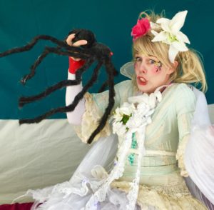 A woman in a costume holding a spider.