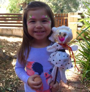 A little girl holding an egg and a doll.