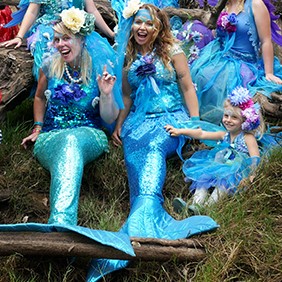 A group of people dressed as mermaids posing for a photo.